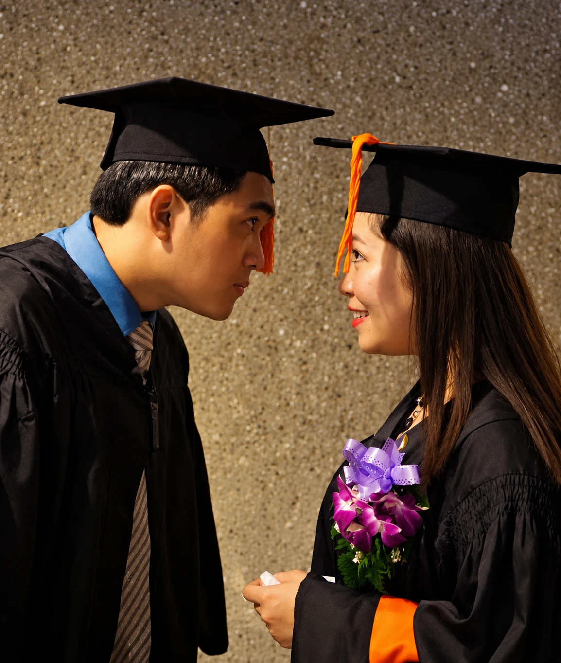 Earvin and Plexy in graduation caps and gowns, smiling at each other