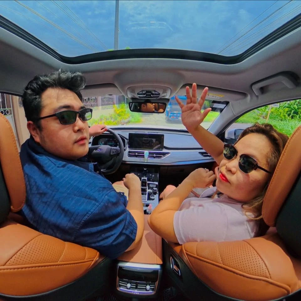 Earvin and Plexy waving from the front seats of their car